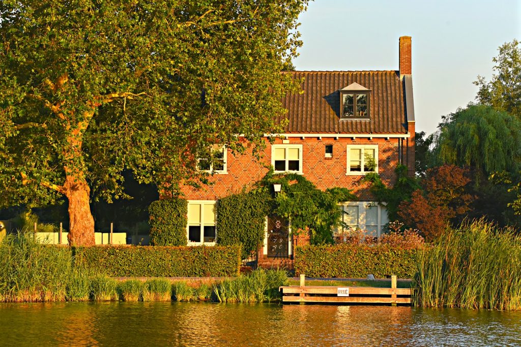 Maison sur la rive d'une rivière avec beaucoup de verdure et un ponton aménagé